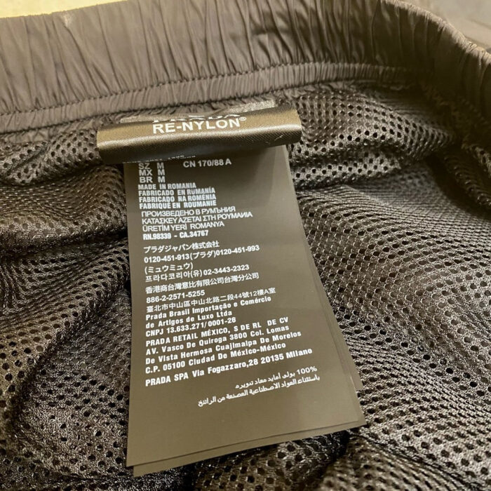 Etichetta di vestito in RE-NYLON riciclato con istruzioni e dettagli sostenibili.