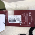 Etichetta del maglione con tag, dettagli, codici e istruzioni di cura.
