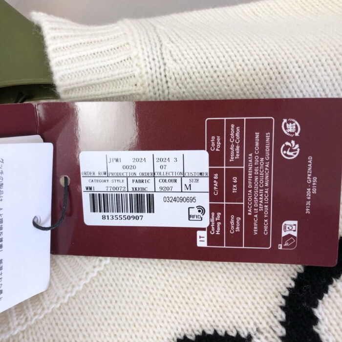 Etichetta del maglione con tag, dettagli, codici e istruzioni di cura.