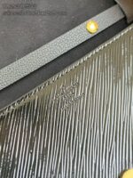 Dettaglio di pelle testurizzata, logo inciso e cinturino in metallo, stile elegante e resistente.