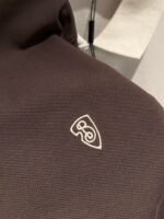 Tessuto marrone scuro con logo bianco moderno e texture resistente, ideale per accessori di moda.