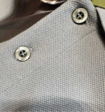 Blusa in cotone grigia con bottoni metallici e tessuto testurizzato elegante.