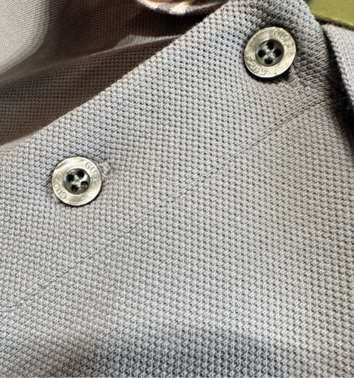 Blusa in cotone grigia con bottoni metallici e tessuto testurizzato elegante.
