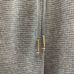 Dettaglio di tessuto grigio e cerniera con inserti sportivi e finiture eleganti.