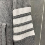 Manica felpa grigia con strisce a rilievo e tasca frontale, stile casual e confortevole.