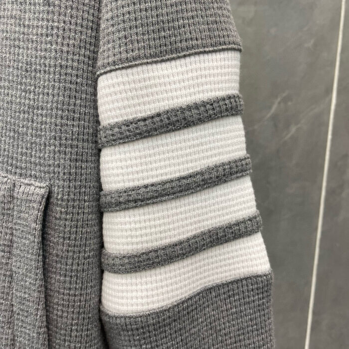 Manica felpa grigia con strisce a rilievo e tasca frontale, stile casual e confortevole.