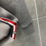 Maglione grigio con colletto a strisce rosso, bianco e blu, stile casual e confortevole.