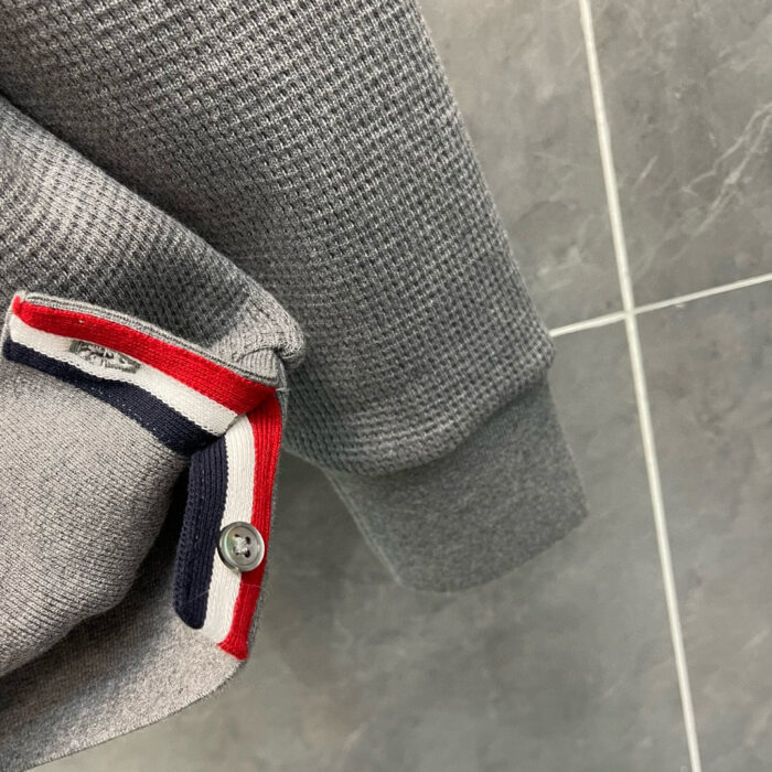 Maglione grigio con colletto a strisce rosso, bianco e blu, stile casual e confortevole.