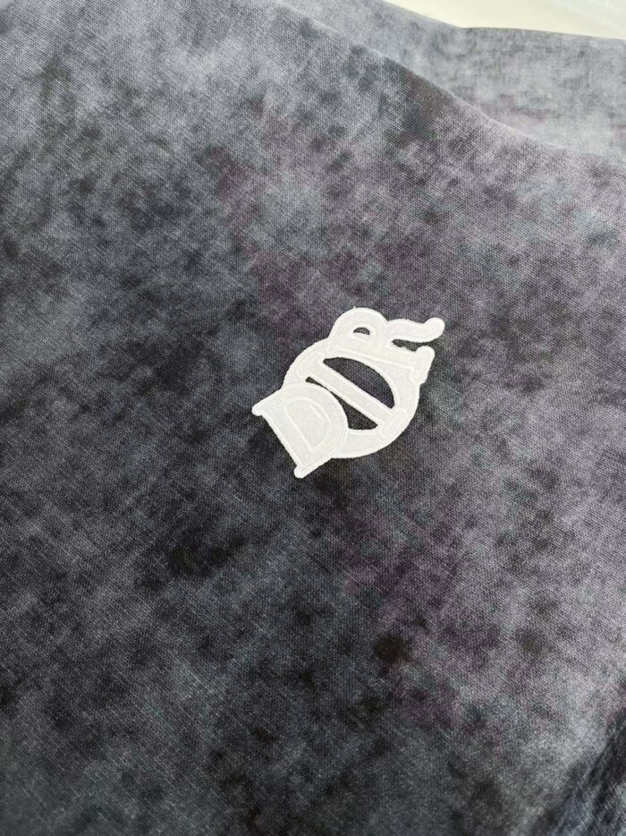 Tessuto viola con logo bianco stilizzato, elegante e morbido, ideale per moda e arredamento.