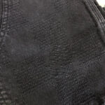 Tessuto nero elegante con motivo intrecciato e dettagli raffinati, ideale per abbigliamento di lusso.