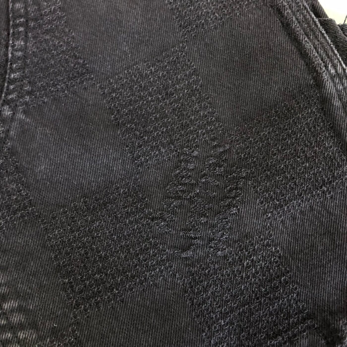 Tessuto nero elegante con motivo intrecciato e dettagli raffinati, ideale per abbigliamento di lusso.