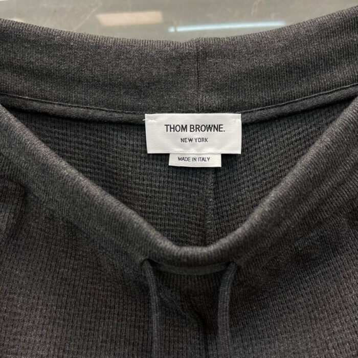 Etichetta Thom Browne Made in Italy, qualità italiana su tessuto grigio morbido ed elegante.