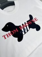 T-shirt bianco Thom Browne con cane stilizzato e dettagli a strisce nero e bianco.