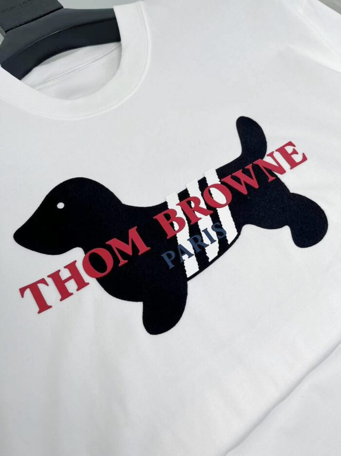 T-shirt bianco Thom Browne con cane stilizzato e dettagli a strisce nero e bianco.