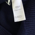 Etichetta Thom Browne su maglione in lana navy, dettaglio di qualità e stile di lusso.