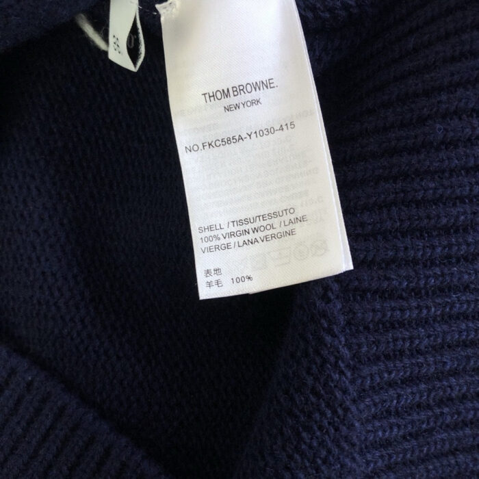 Etichetta Thom Browne su maglione in lana navy, dettaglio di qualità e stile di lusso.