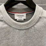 Maglia grigia Thom Browne con logo, dettaglio colorato e qualità Made in Japan.