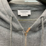 Felpa grigia Thom Browne con zip, realizzata in Italia, elegante e confortevole.