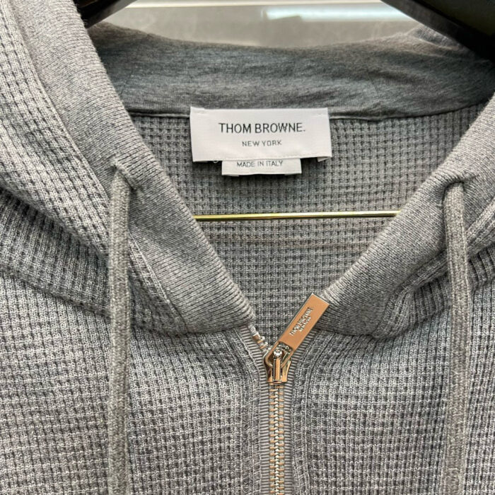 Felpa grigia Thom Browne con zip, realizzata in Italia, elegante e confortevole.