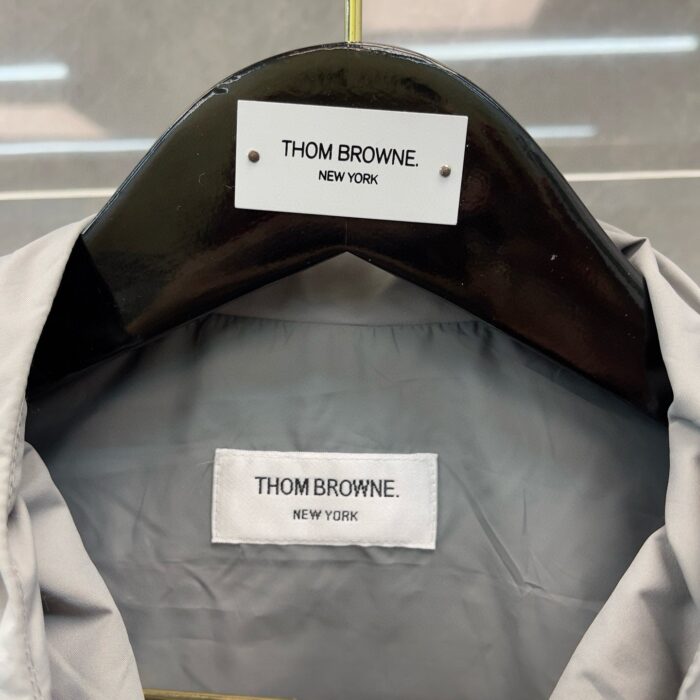 Etichetta di lusso Thom Browne Milano Moda Uomo, dettagli branding e tessuto elegante.