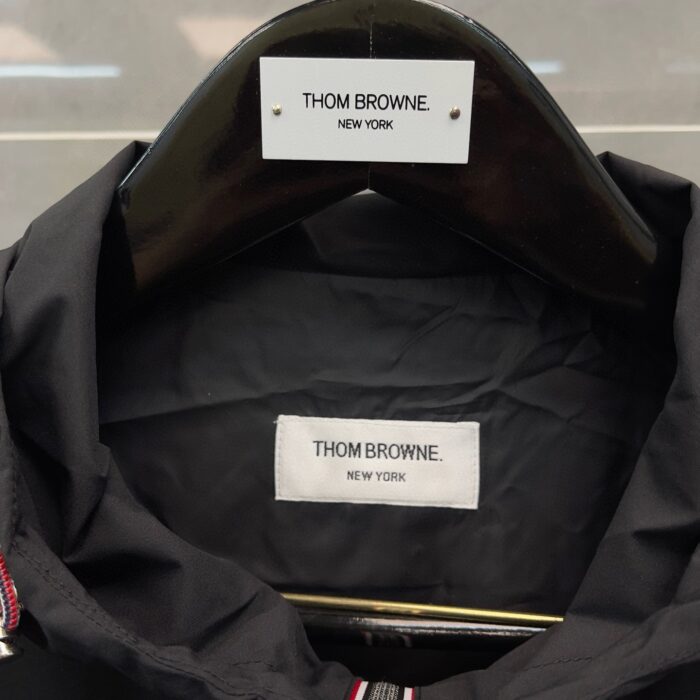 Giacca Thom Browne con etichetta elegante, collare nero e design di alta qualità.
