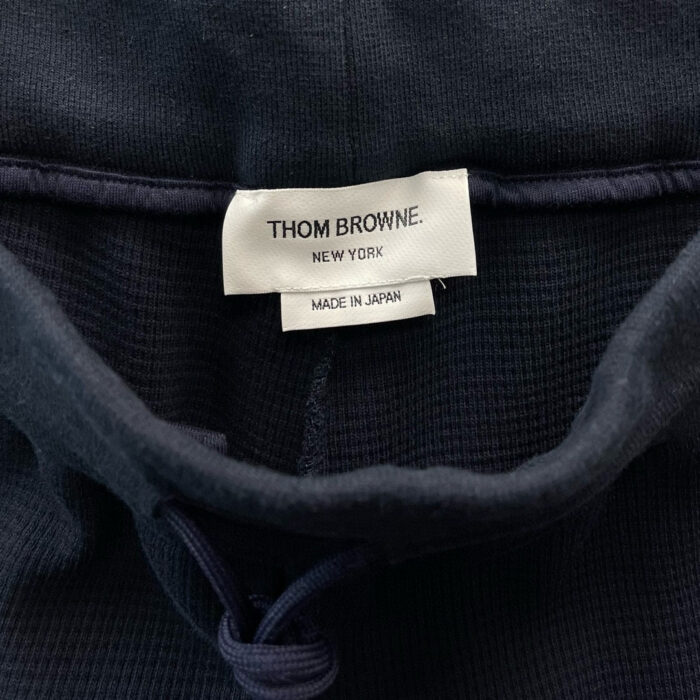 Etichetta Thom Browne Made in Japan su maglione navy, moda di lusso e qualità italiana.