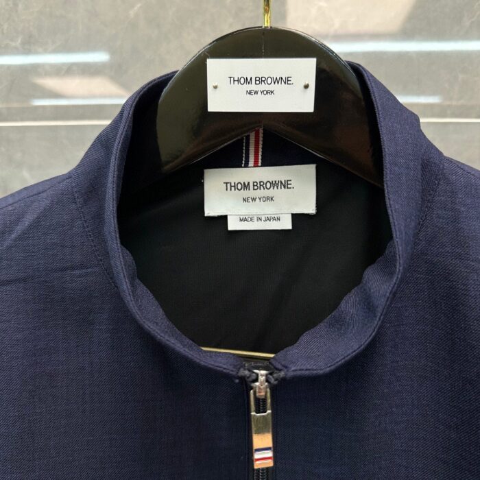 Giacca Thom Browne navy con zip, colletto a punta e dettagli colorati, Made in Japan.
