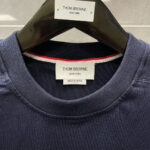 Etichetta Thom Browne navy made in Japan con dettaglio a strisce sul colletto.