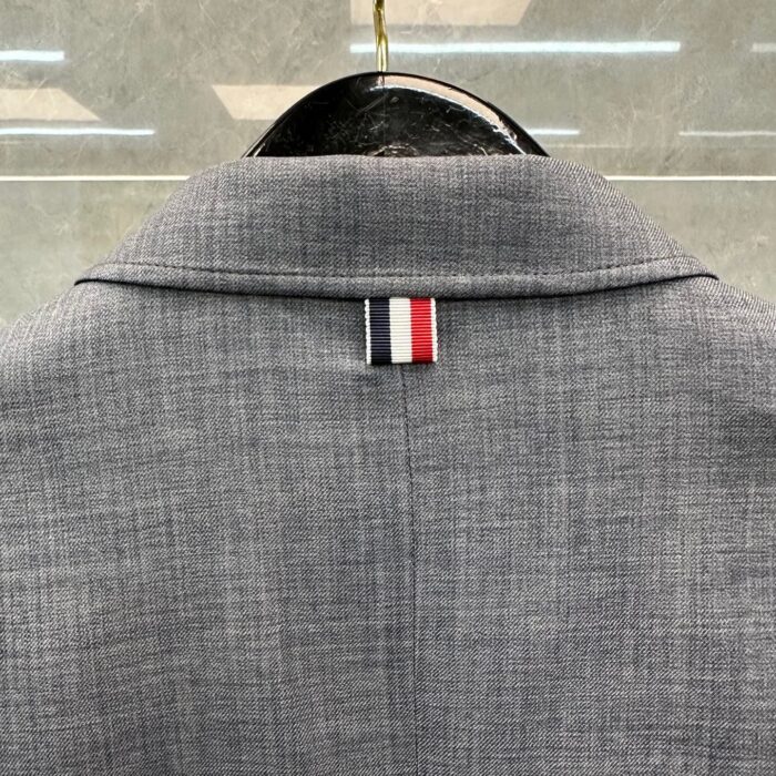 Elegante giacca sartoriale con dettaglio della bandiera tricolore rosso, bianco e blu.
