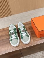 Sneakers eleganti verde e crema con scatola di lusso su superficie in legno lucido.