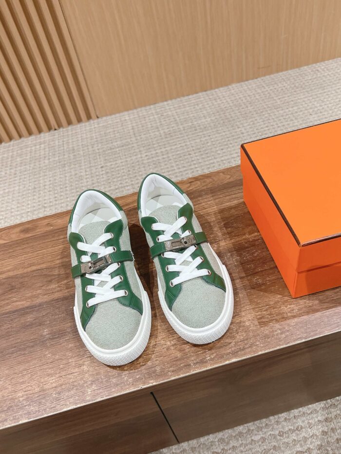 Sneakers eleganti verde e crema con scatola di lusso su superficie in legno lucido.