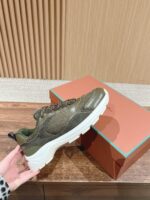 Sneaker casual e elegante in verde oliva e grigio scuro, con suola bianca e dettagli moderni.