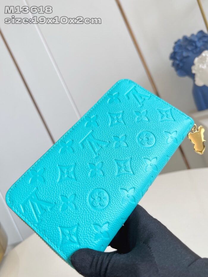 Portafoglio in pelle turchese con dettagli in oro e monogrammi di lusso.