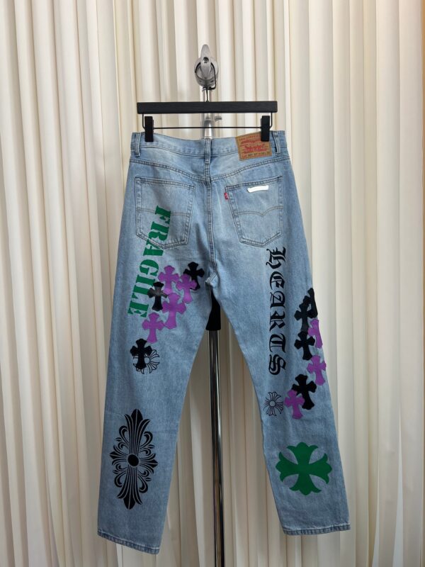 Jeans blu chiaro con ricami floreali e scritte artistiche, stile streetwear.