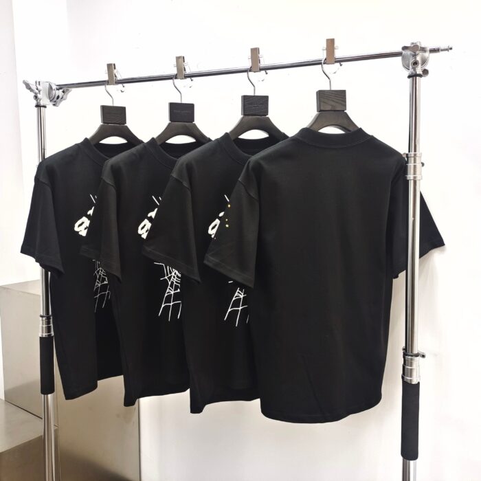 Magliette nere con logo, esposizione moderna su rastrelliera in metallo lucido.