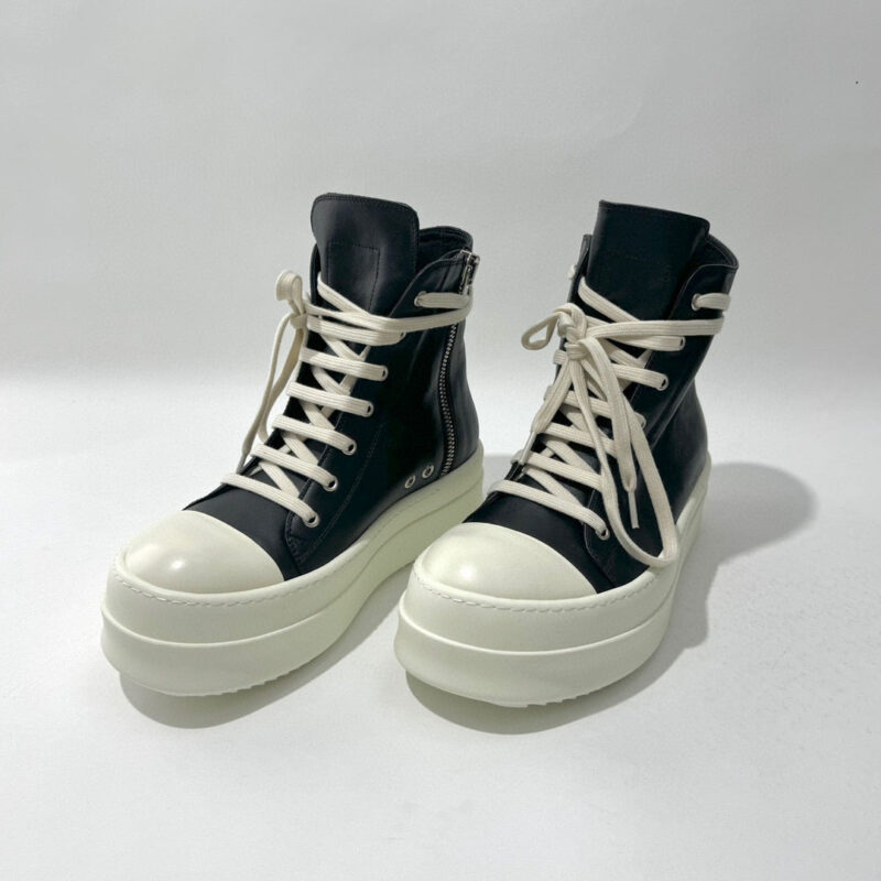 Sneakers alte nere moderne con suola bianca, zip laterale e stile urbano trendy.