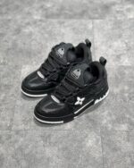 Sneakers nere moderne con dettagli in pelle e tessuto, stile urbano e casual, su sfondo grigio.