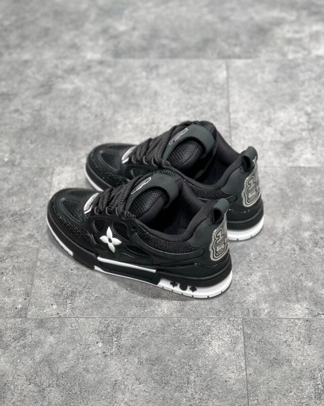 Sneakers nere moderne con dettagli bianchi, logo riflettente e suola antiscivolo, stile urbano e versatile.