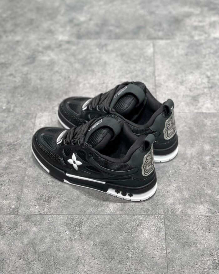 Sneakers nere moderne con dettagli bianchi, logo riflettente e suola antiscivolo, stile urbano e versatile.