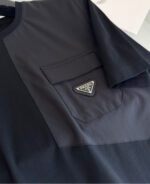 T-shirt nero con tasca, logo minimalista in metallo, stile moderno e versatile.