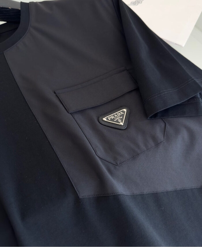 T-shirt nero con tasca, logo minimalista in metallo, stile moderno e versatile.