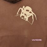 Felpa marrone con grafica astratta di ragno e dettagli rosa moderno, stile streetwear urban.
