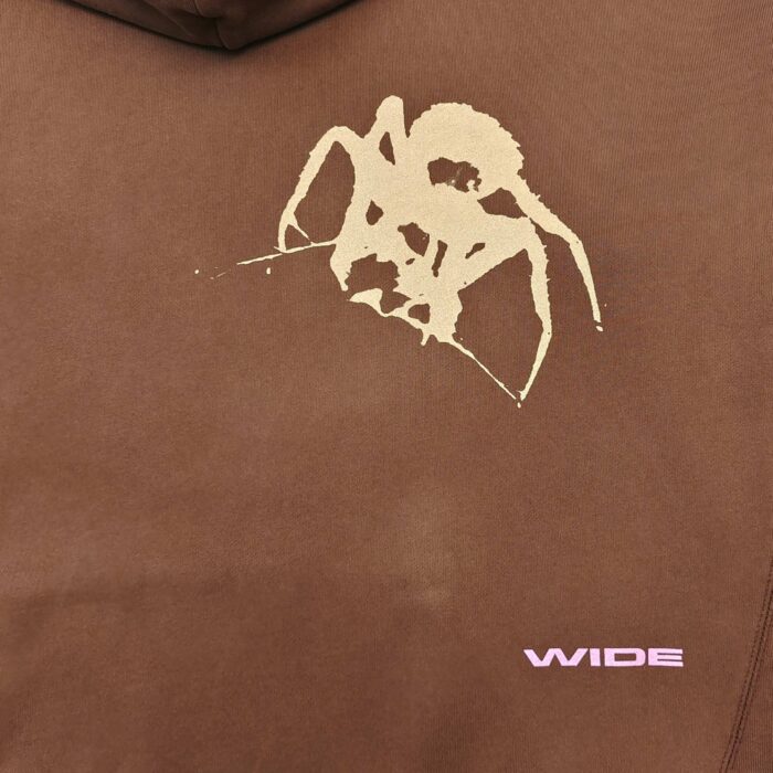 Felpa marrone con grafica astratta di ragno e dettagli rosa moderno, stile streetwear urban.