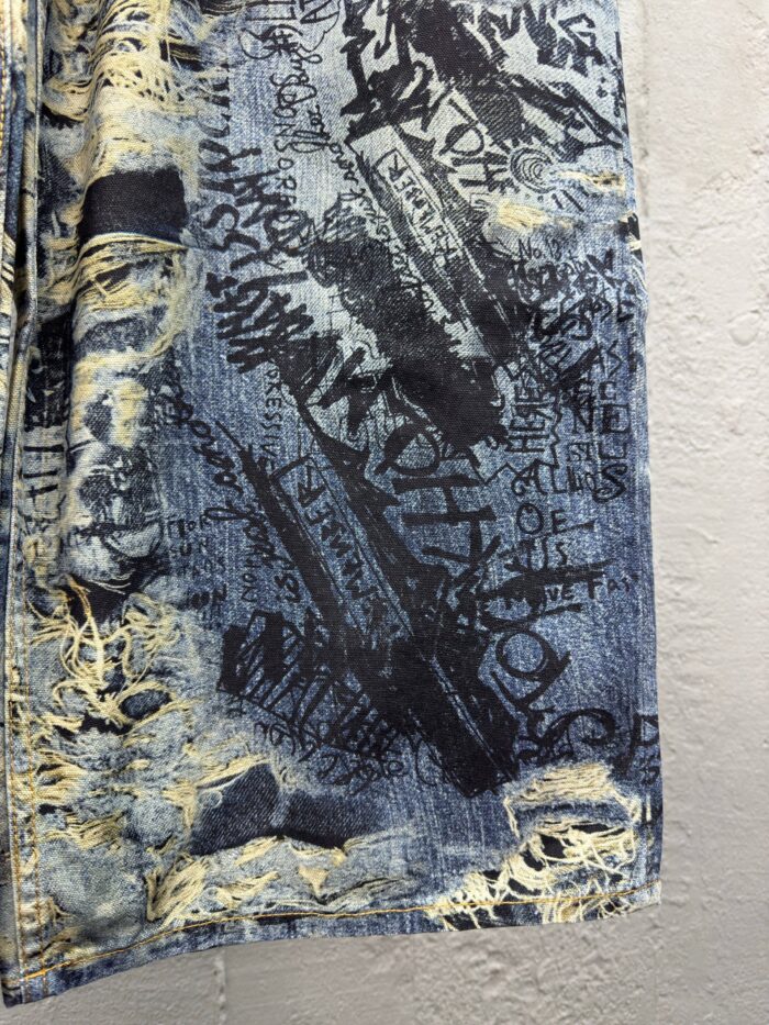 Shorts in denim con graffiti, scritte artistiche e rotture urbane, stile casual e trendy.