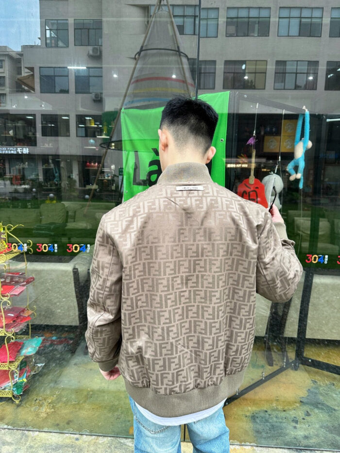Giovane uomo in bomber Fendi e jeans chiari in un vivace contesto urbano.