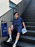 Ragazzo in abbigliamento casual seduto sulle scale urbane con rivista e stile moderno.