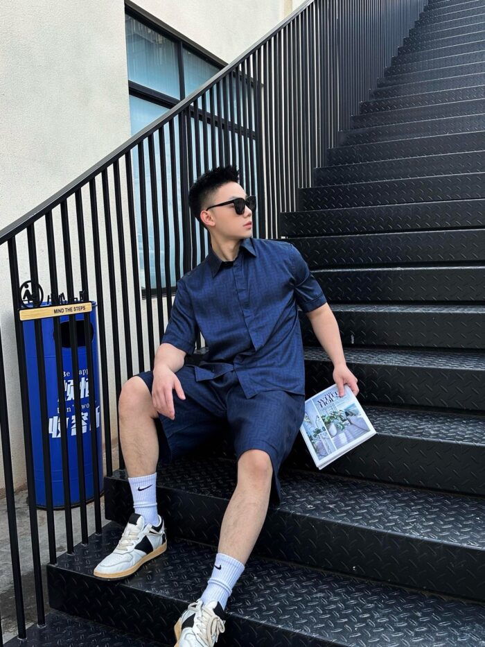 Ragazzo in abbigliamento casual seduto sulle scale urbane con rivista e stile moderno.