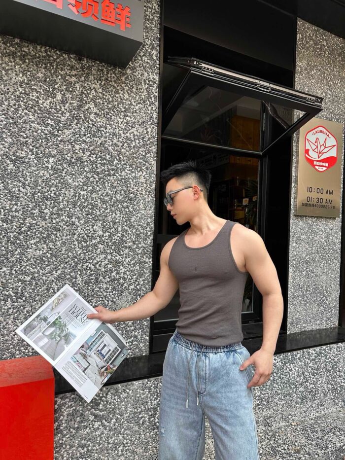 Giovane uomo casual che legge un giornale davanti a edificio moderno in ambiente urbano.