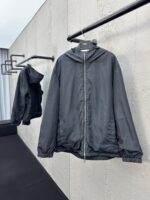 Giacca minimalista in grigio scuro su sfondo in cemento, stile contemporaneo e pratico.