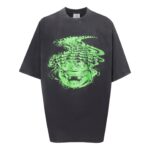 T-shirt oversize grigia con grafica di volto distorto verde, stile streetwear moderno e casual.